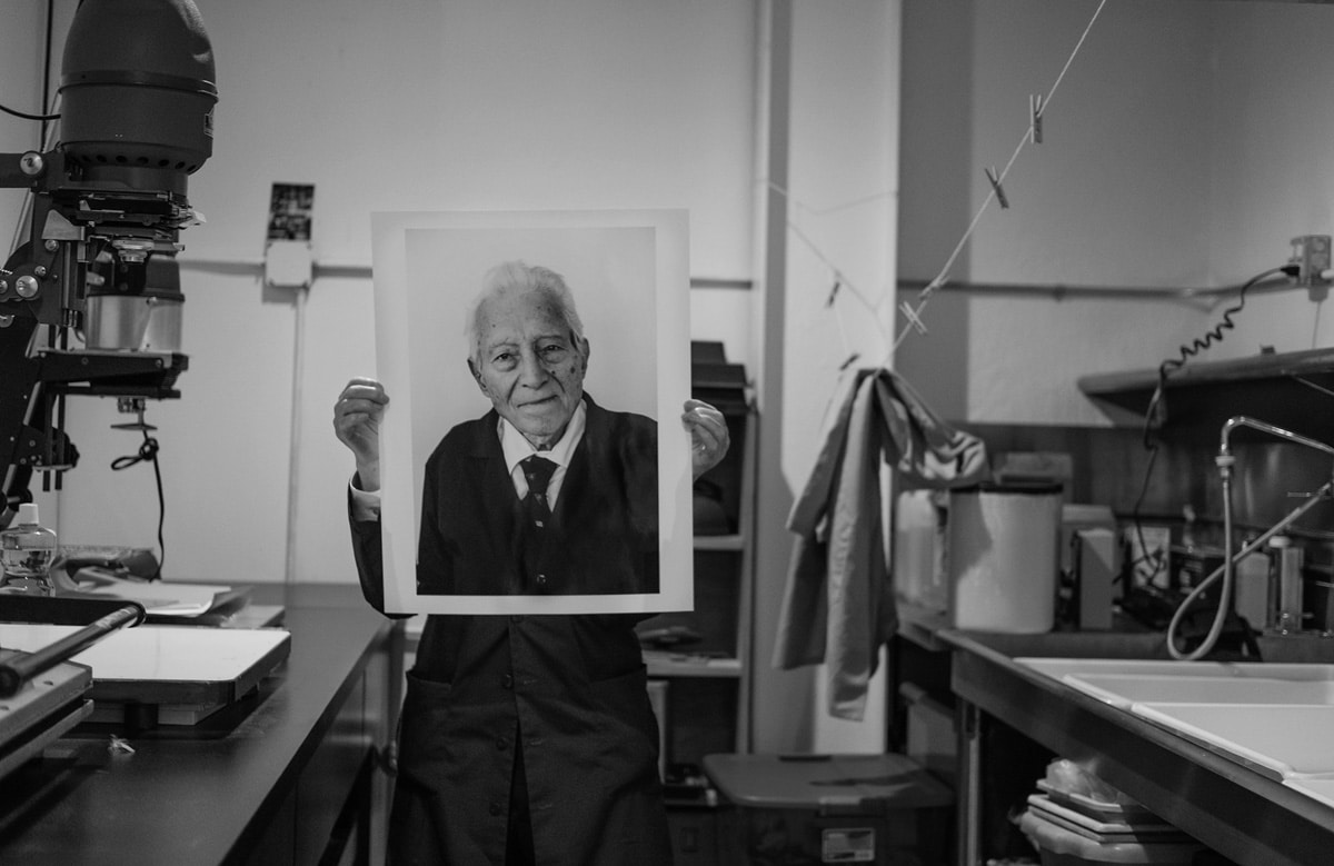 IMAGE: Tony Vaccaro holding a print of himself in his studio - https://emulsive.org/wp-content/uploads/2018/07/Tony-holding-Tony.jpg