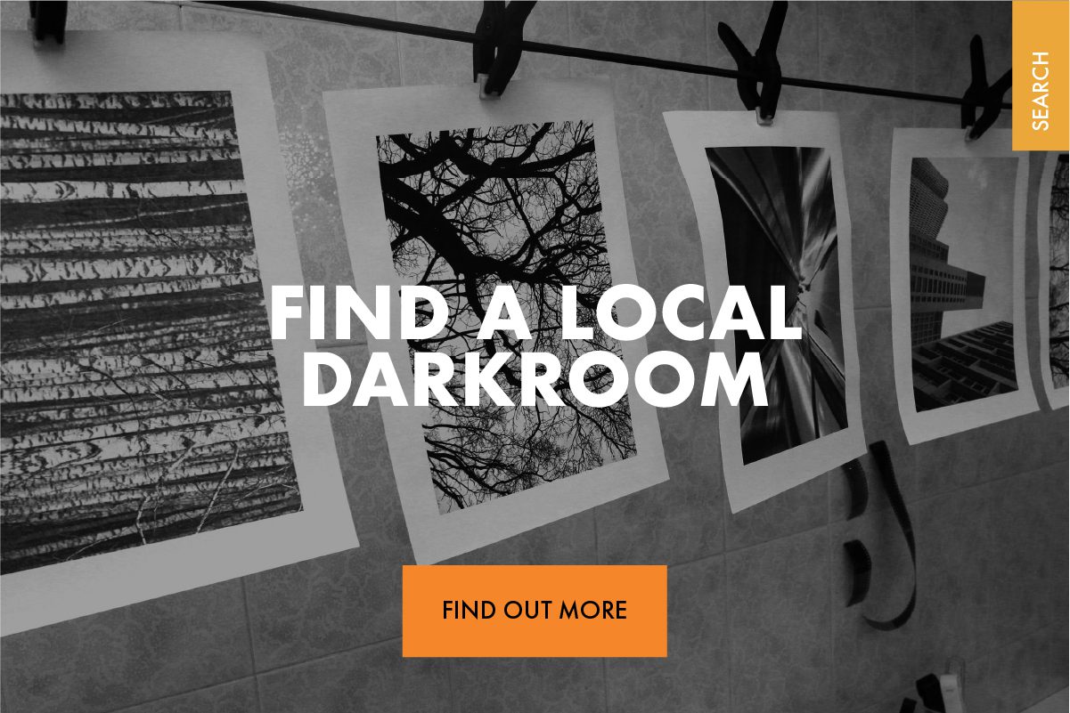Image shows black and white darkroom prints hanging to dry. The text 'Find a local Darkroom' is centered on the image