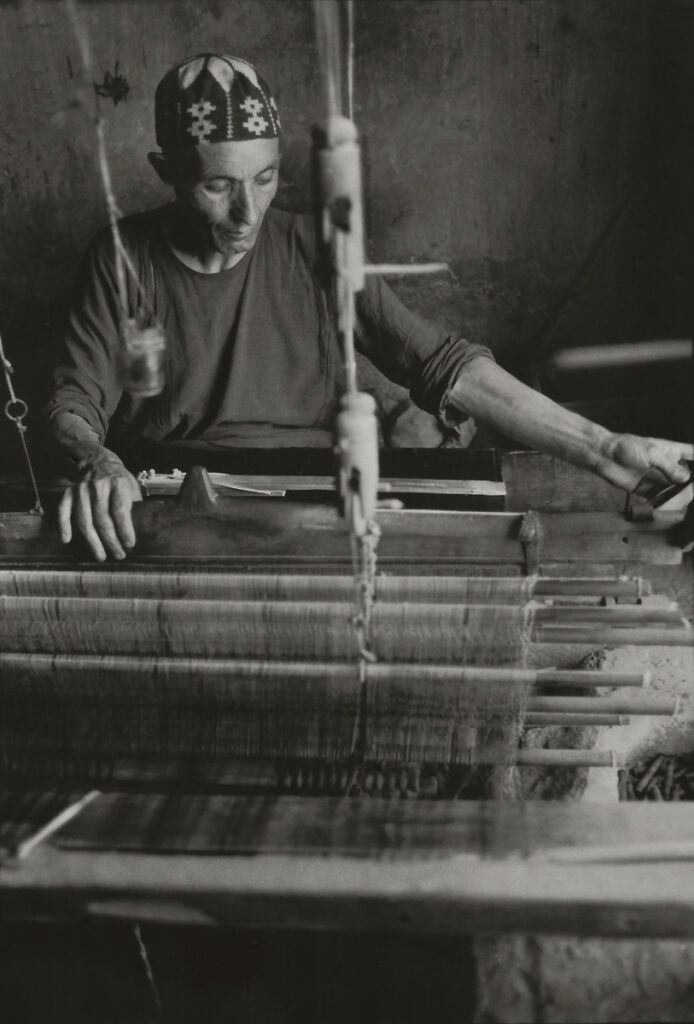 Black and white photograph of a man weaving