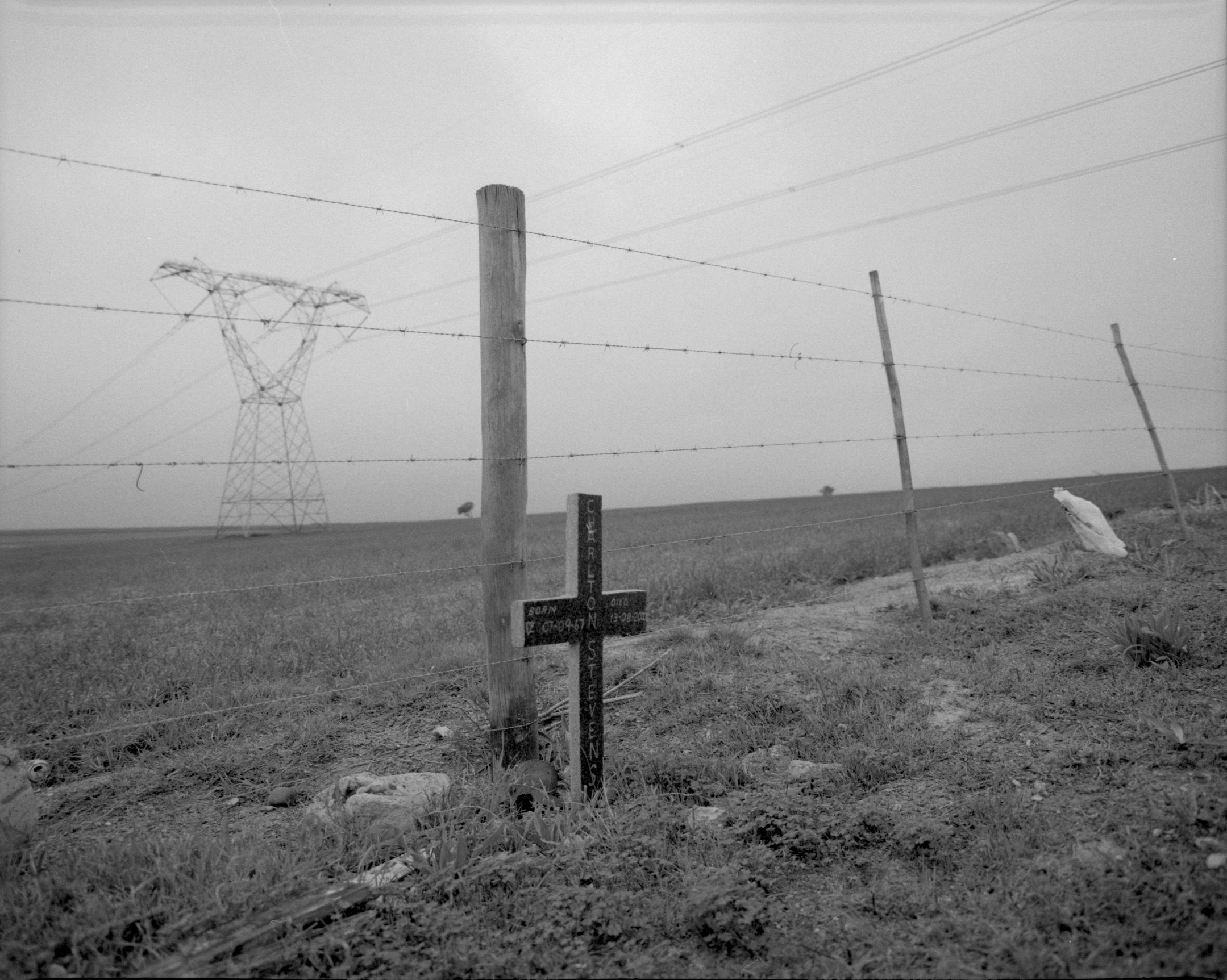 Black and white image of a field with a cross as the focal point