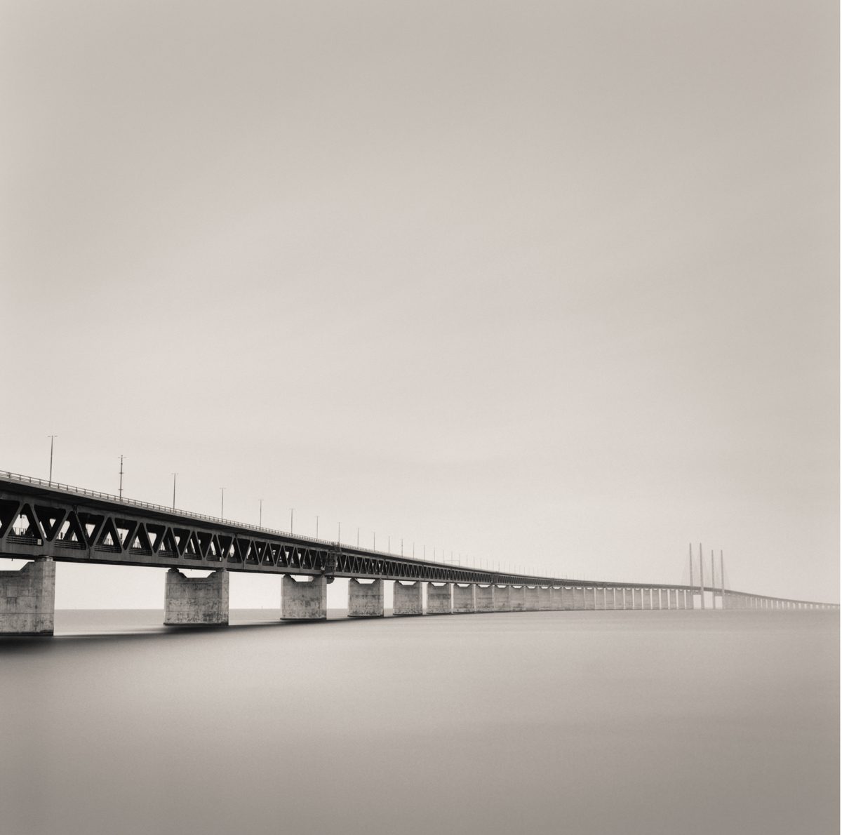 Black and white photograph of a bridge along the misty seascape
