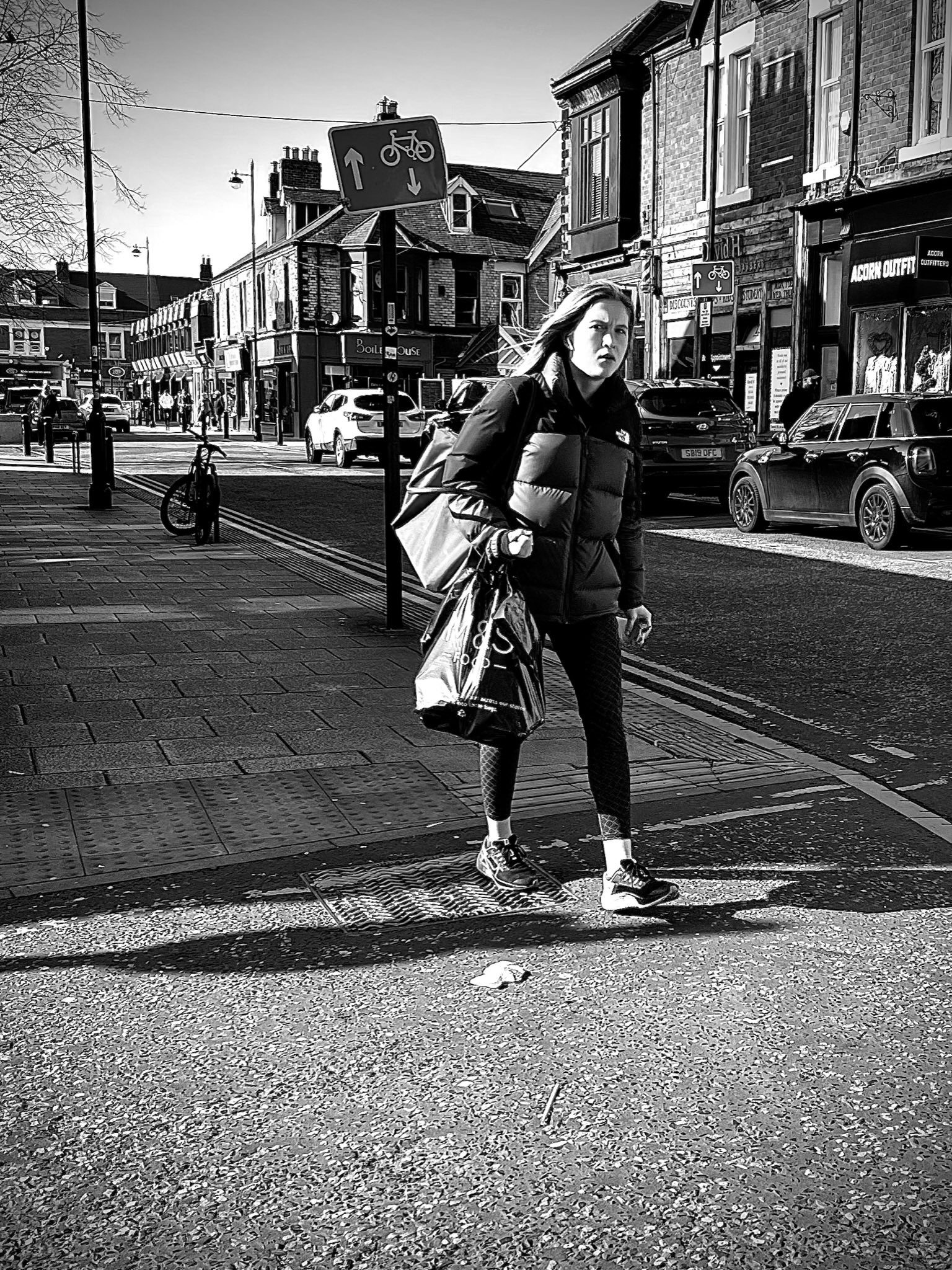 Black and white street photography of a women walking down the high street shot for ILFORD Photo #FridayFavourites #sheshootsilford