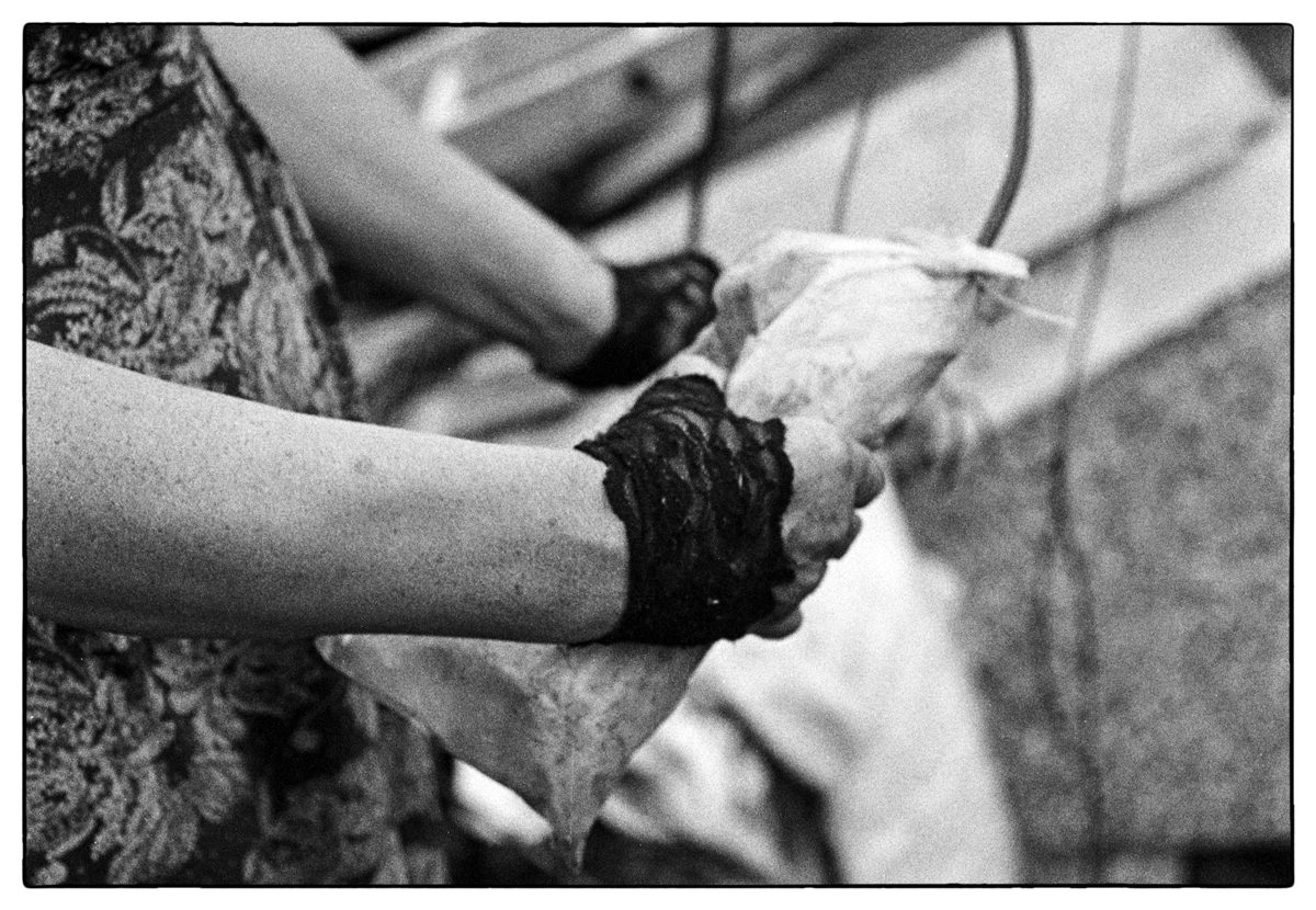 Black and white photo of a hand with black lace fingerless gloves holding an item outside