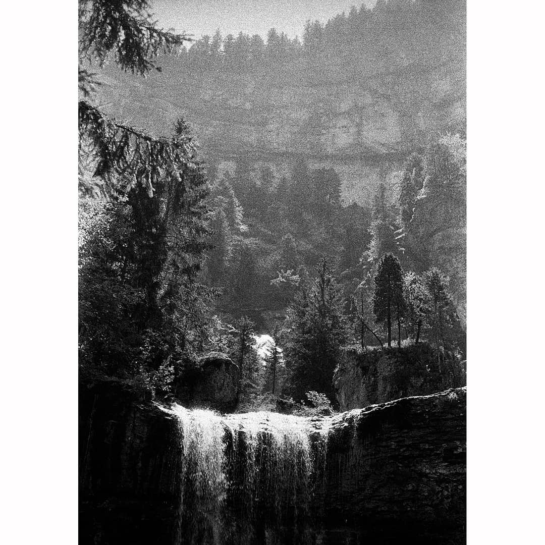 Black and white grainy photograph of a landscape with a waterfall