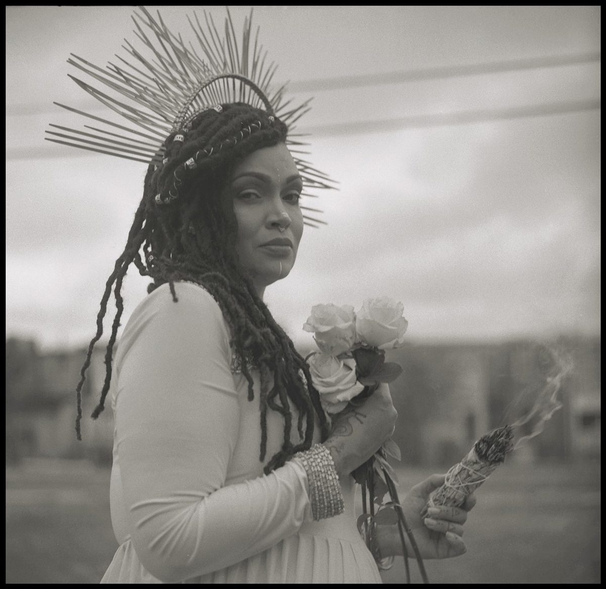 Black and white portrait of woman holding flowers with a headpiece