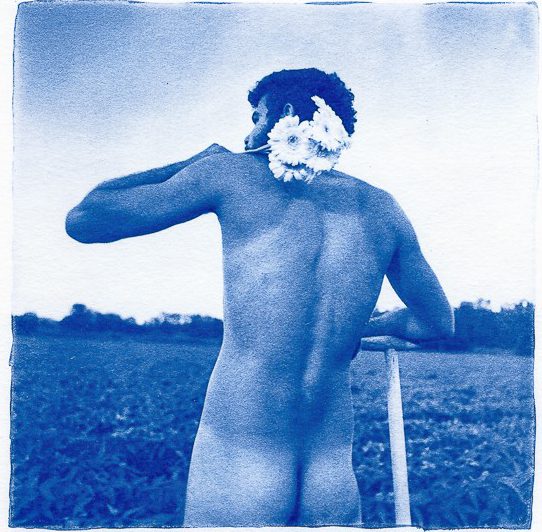Blue cyanotype print of a naked man holding flowers along his neck
