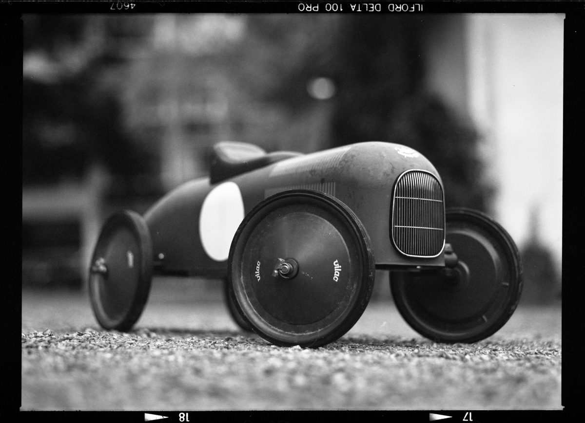 Black and white still life photography of a toy car on the floor