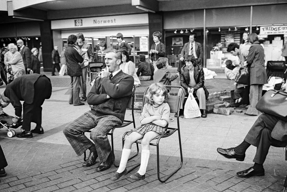 Black and white photo of a man and young girl sat down in Stockport town centre