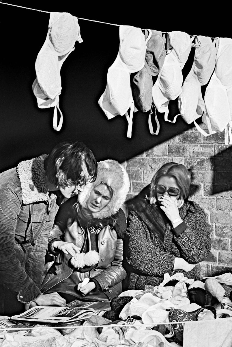 Three ladies talking with one another at a market stall