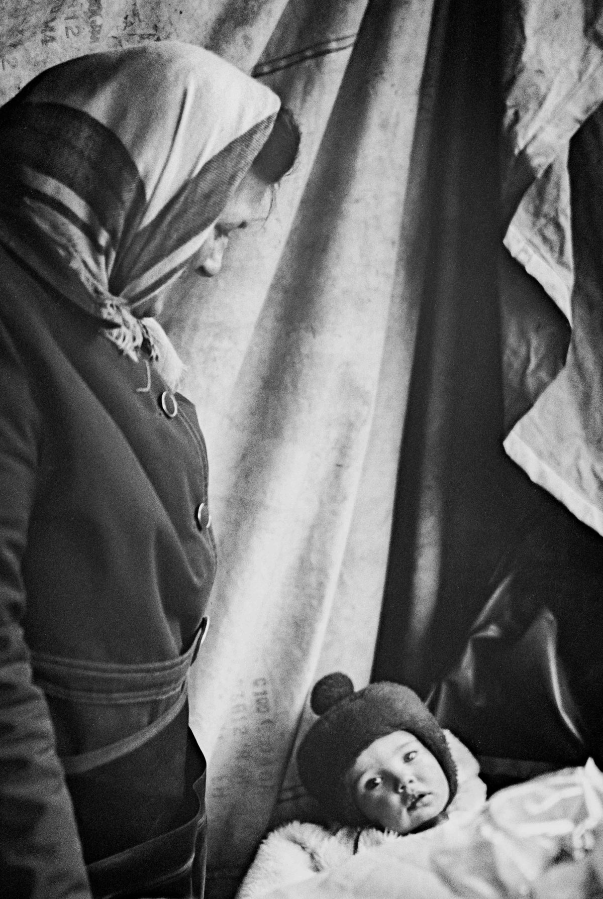 Black and white photo of a woman with a baby looking into the camera