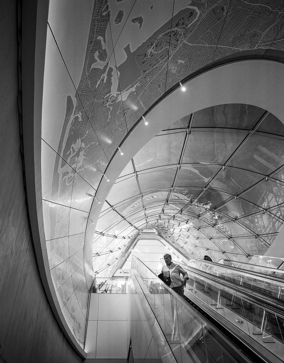 Black and white photo of the ceiling going up an esculator