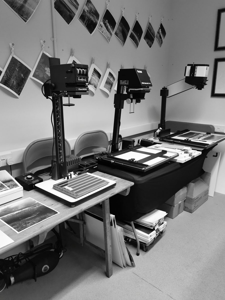 Black and white image of enlargers in the darkroom