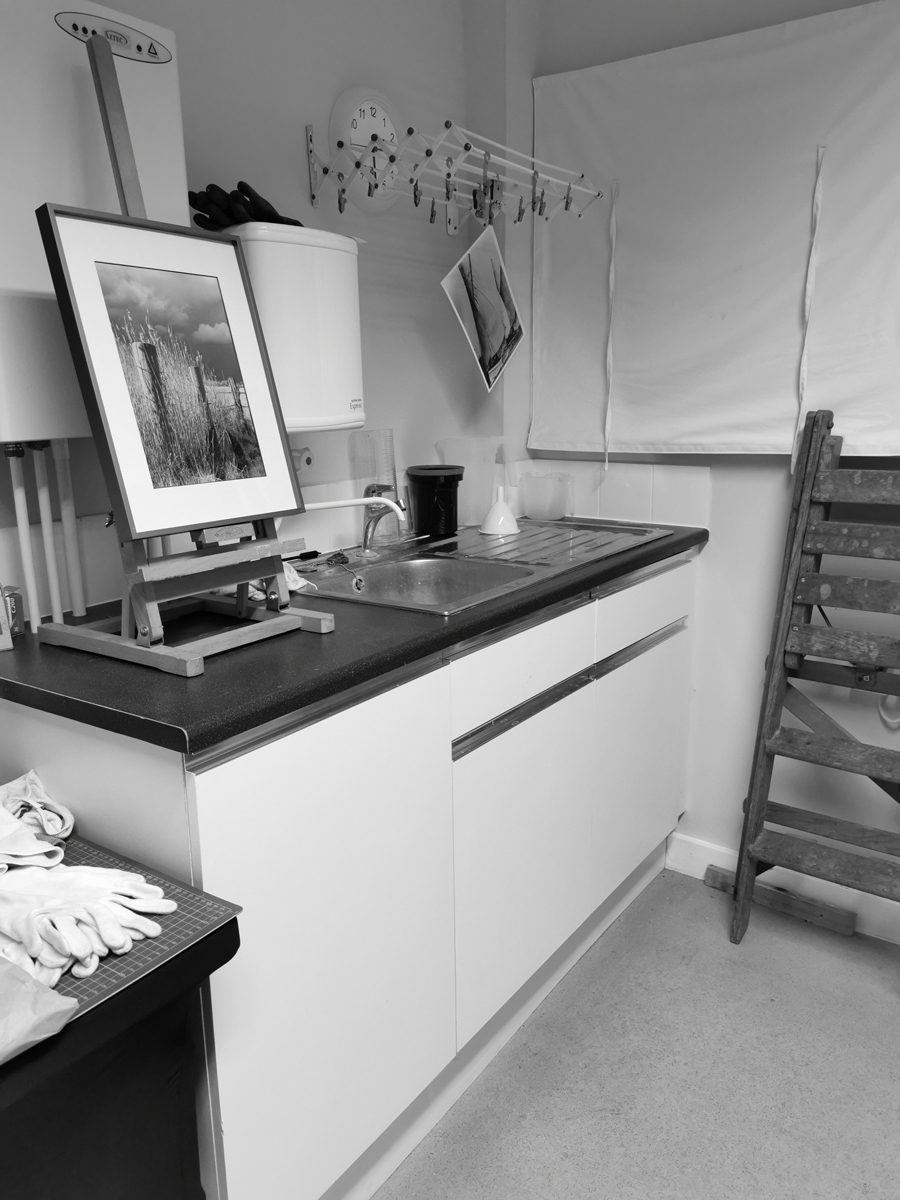 Black and white photograph of the sink in the darkroom with areas to hang prints
