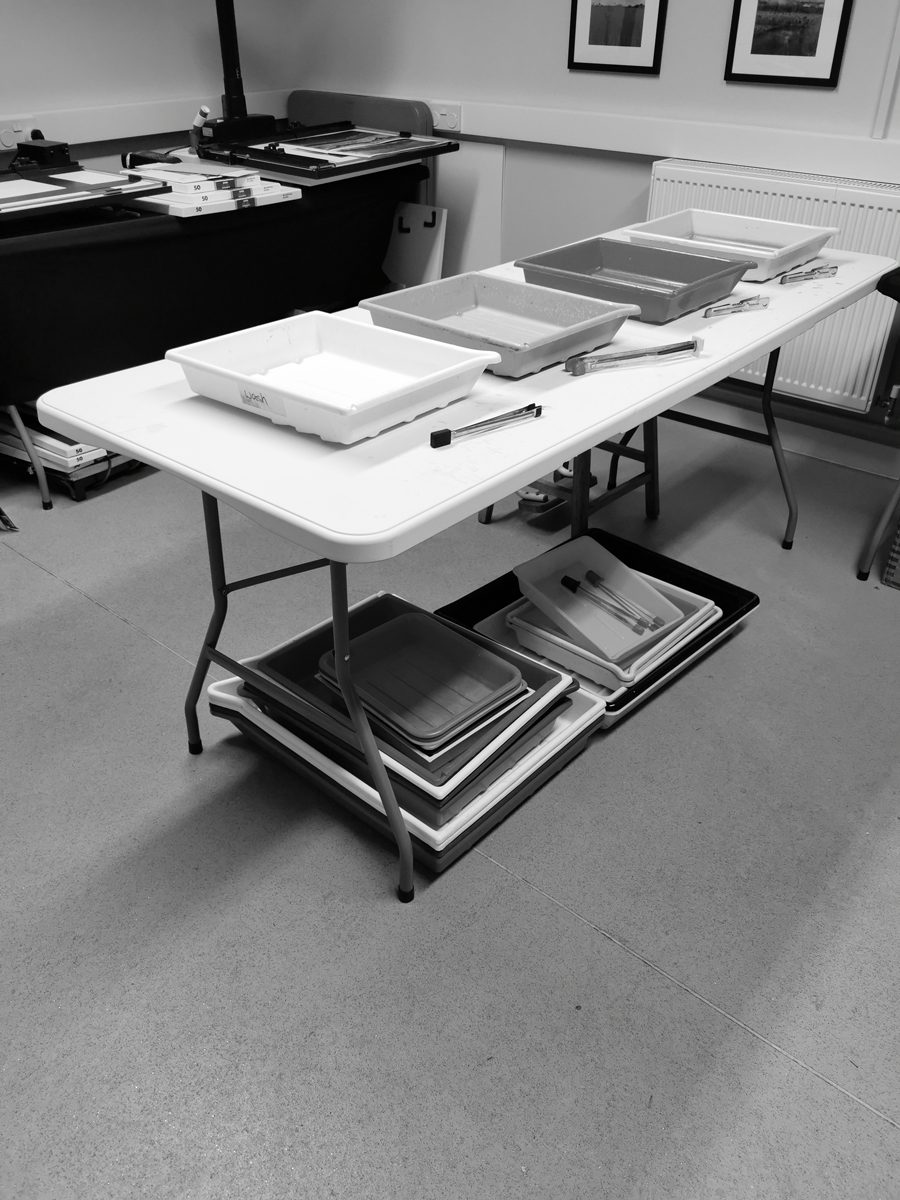 Black and white image of chemical trays for the darkroom lines up
