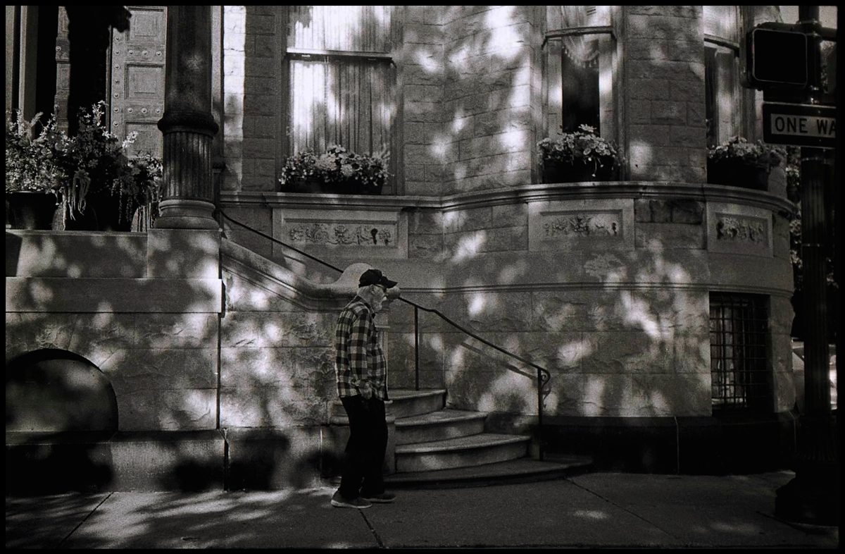 Black and white photo of a street with someone walking past the camera