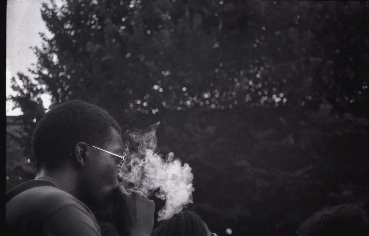 Black and white photo of a girl smoking with the smoke in the air