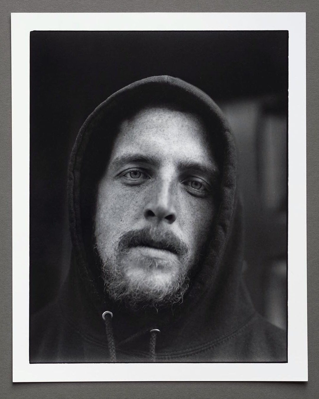 Black and white darkroom print of a portrait of a man with his hood up over his head