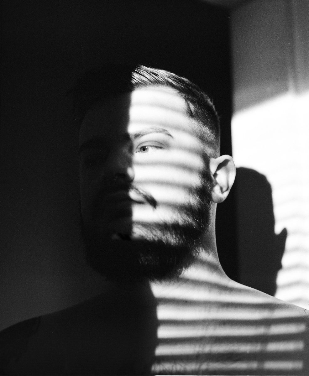 Black and white portrait of a male with a show over his face