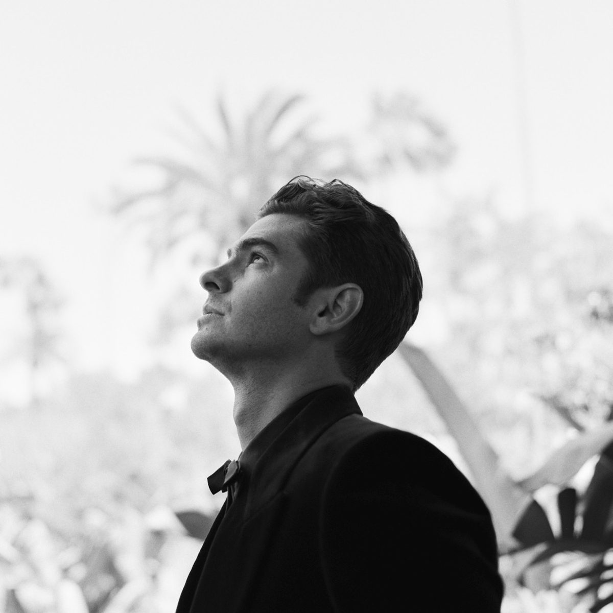 Portrait of a celebrity looking up with a tree behind him