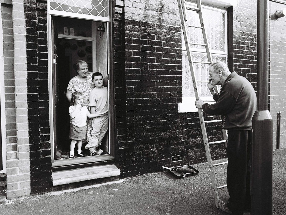 Old man taking a picture of his family through the door