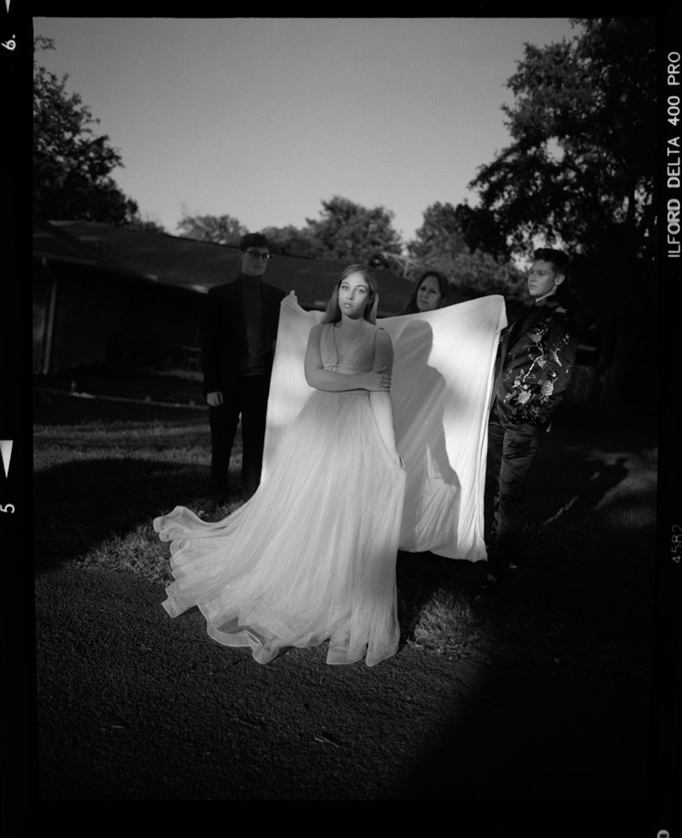 Posing in front of a white sheet with a dress on for prom