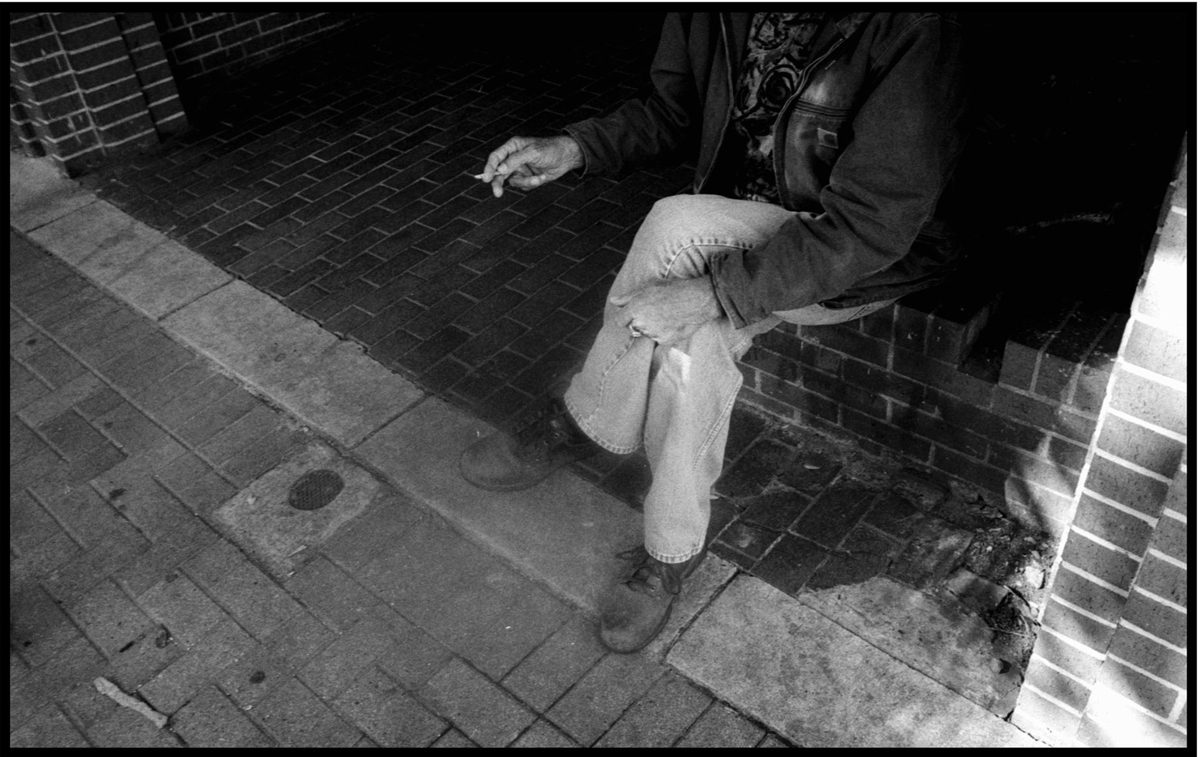 Man sat down holding a cigarette