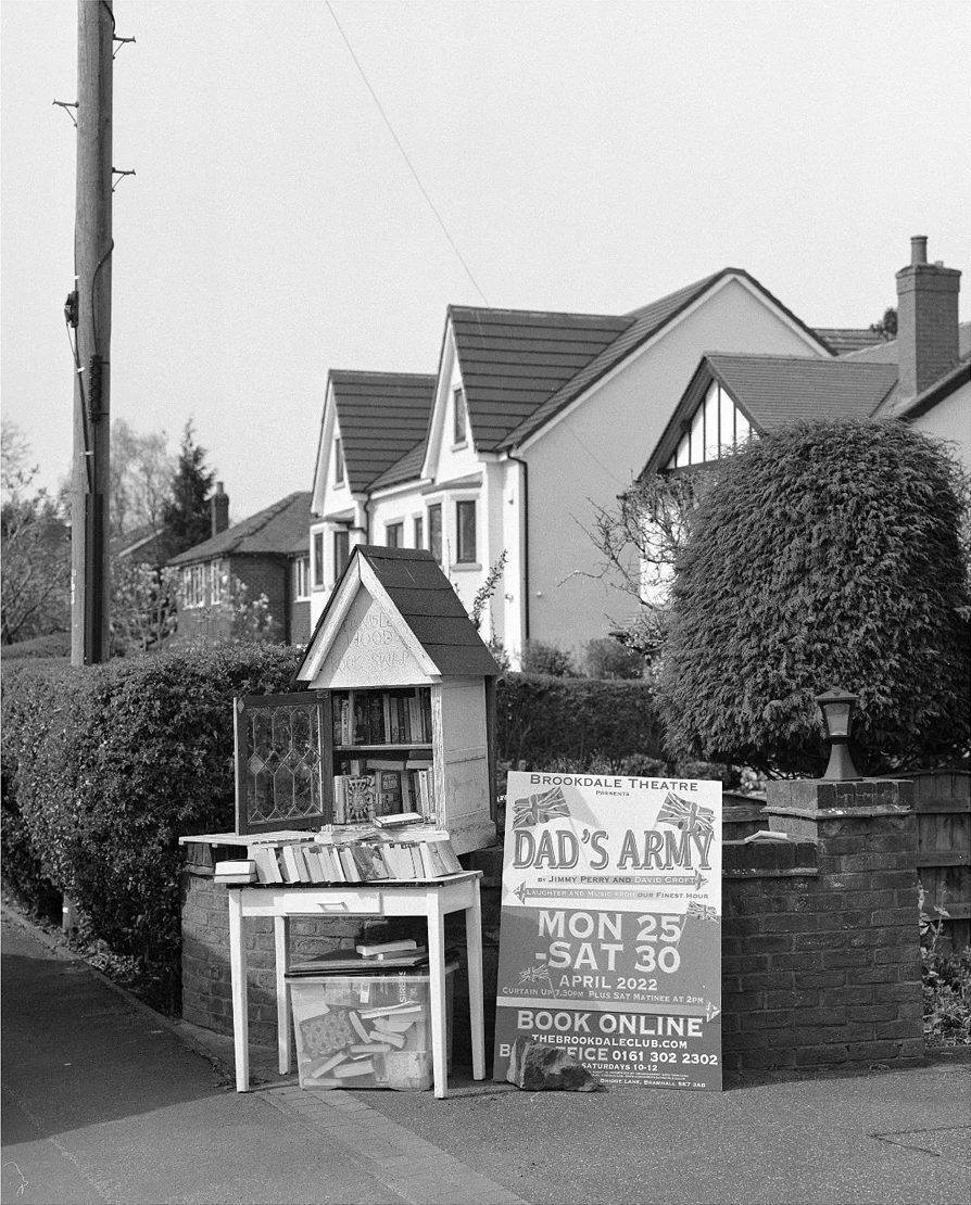 Black and white photo of houses with a sign infront and books