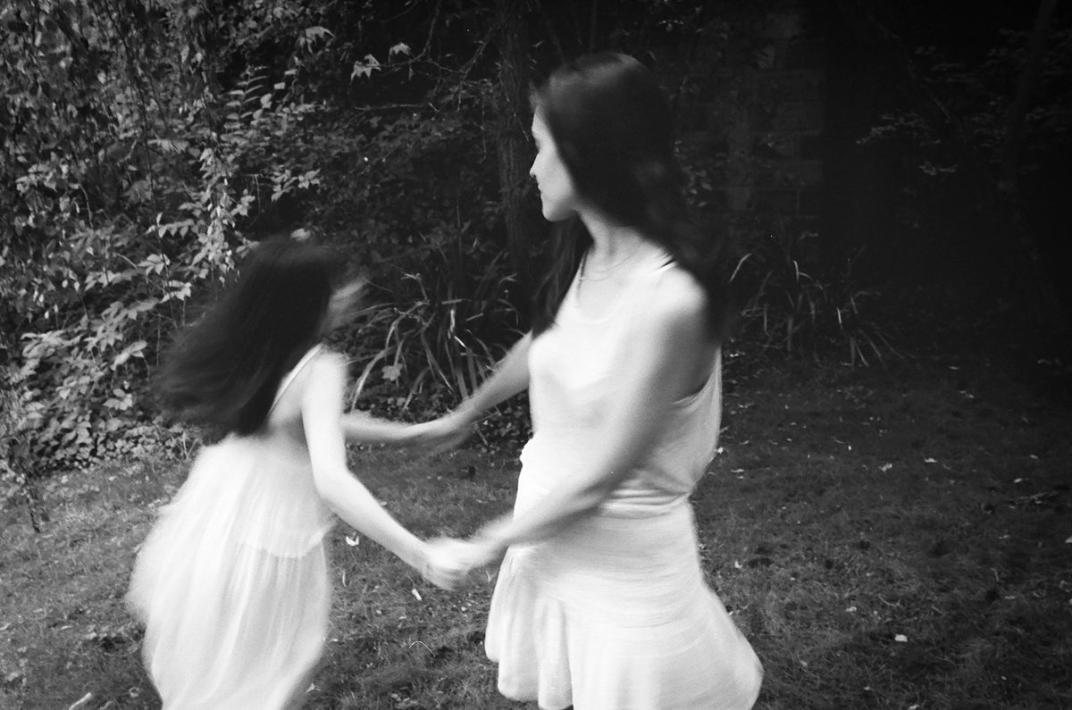 Black and white photo of two girls holding hands and dancing