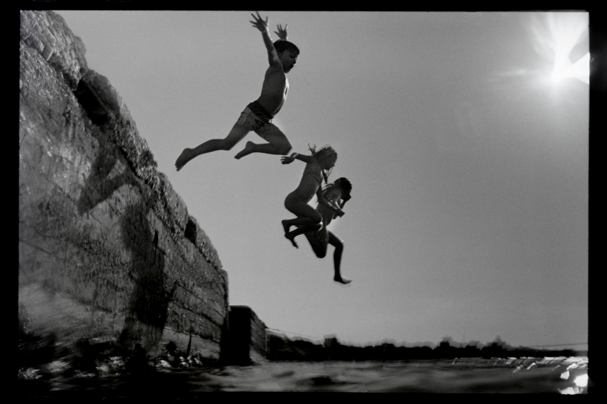 Three people jumping off into the sea