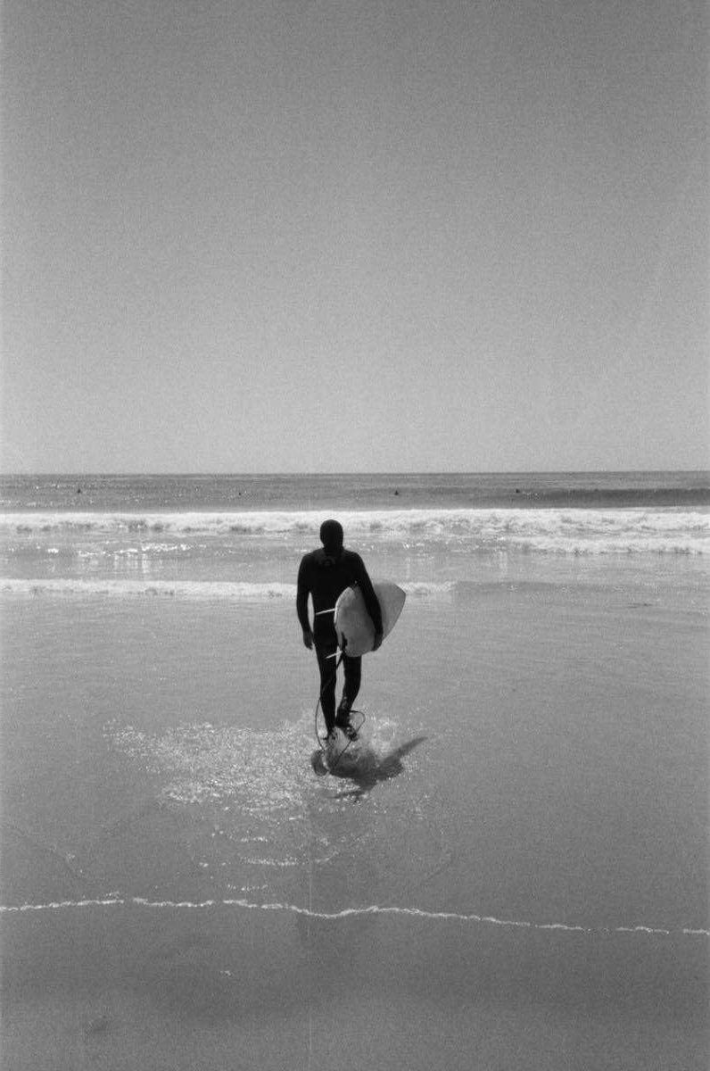 Someone walking into the sea with a surfboard