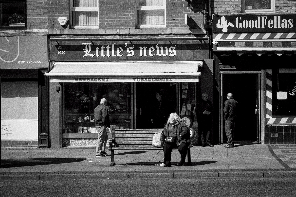 lady sat on a bench outside a shop on the street