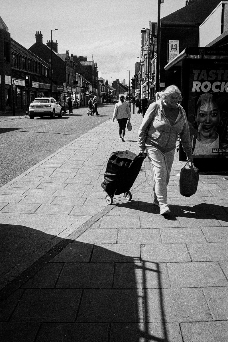 Old lady walking down a street with a trolley