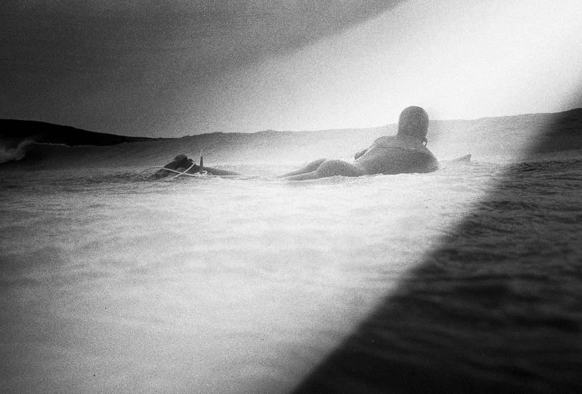 A person lay down on a surfboard in the ocean