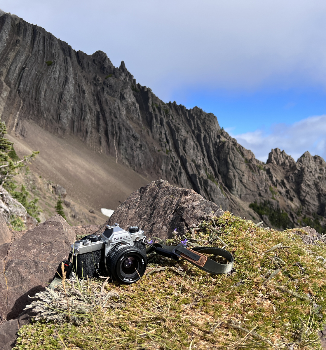 Nikon FM camera lay on the grass in front of a mountain