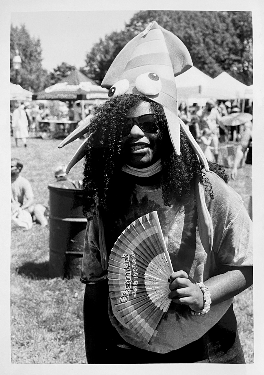 Young girl with a squid hat on while holding a fan