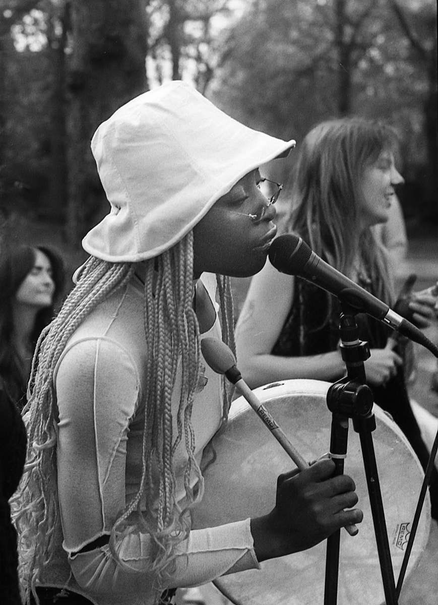 Woman of colour with dreadlocks singing into a micraphone