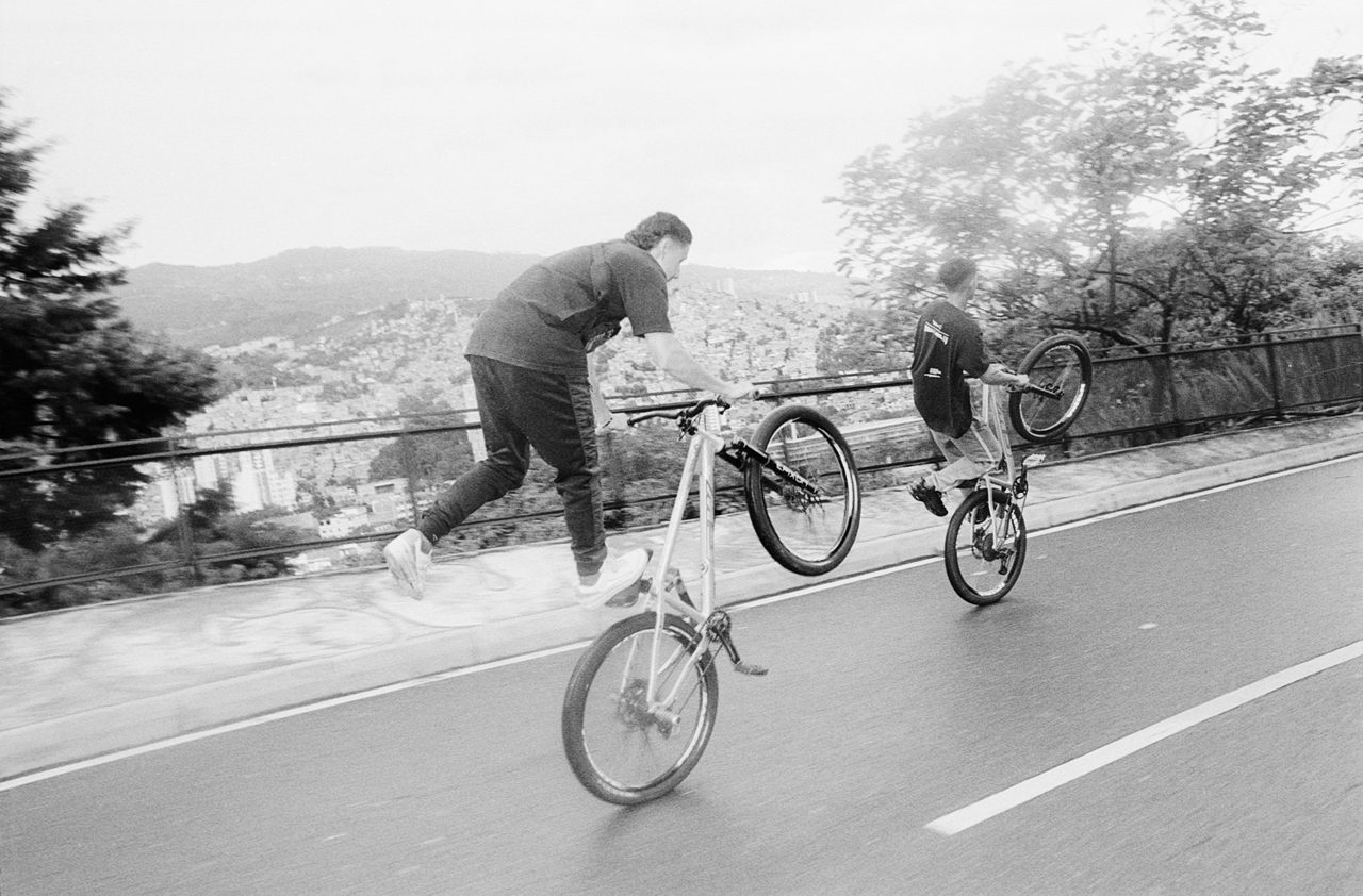Henry Craver. Black and white shot of a guy doing a wheelie on a bike.