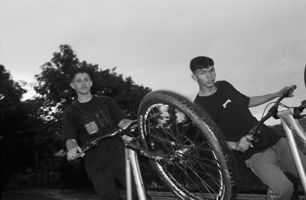 Henry Craver. Black and white shot of a guy doing a wheelie on a bike.