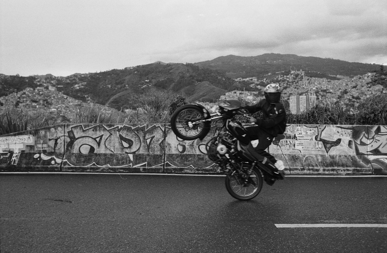 Henry Craver. Black and white shot of a guy doing a wheelie on a bike.