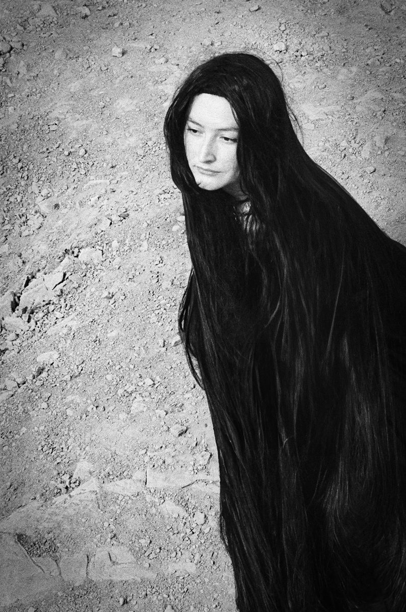 Black and white shot of a woman with long her dressed in black