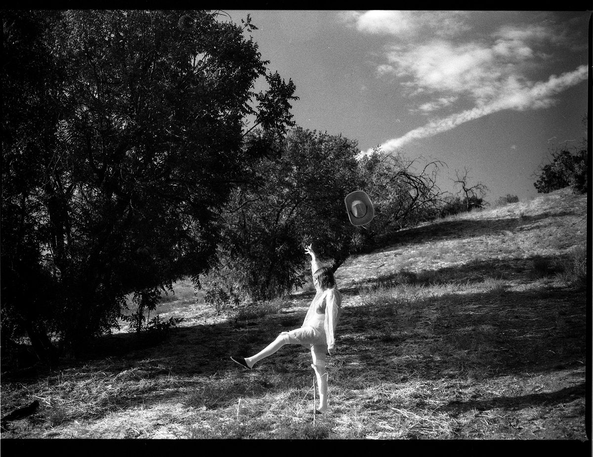 Black and white shot of a woman dancing in a field