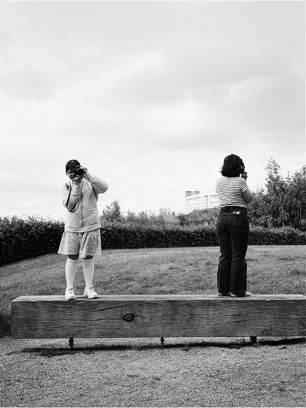 Black and white portrait of two people stood on a bench
