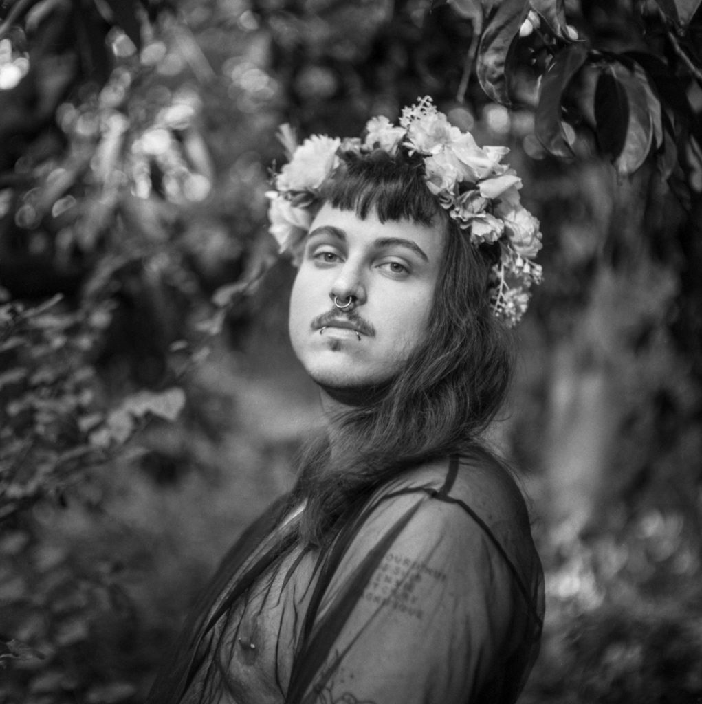 Black and white picture of a man posing in the woods