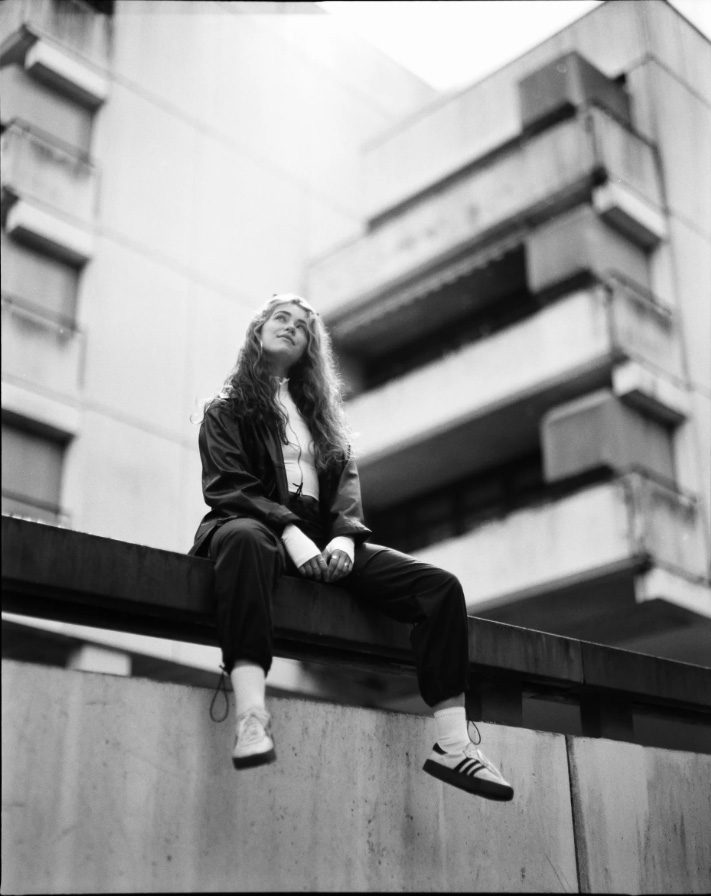 Black and white portrait of a woman sat on a wall