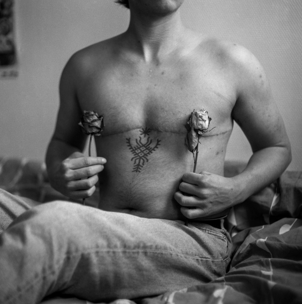 Black and white portrait of a body and the person holding flowers in front 