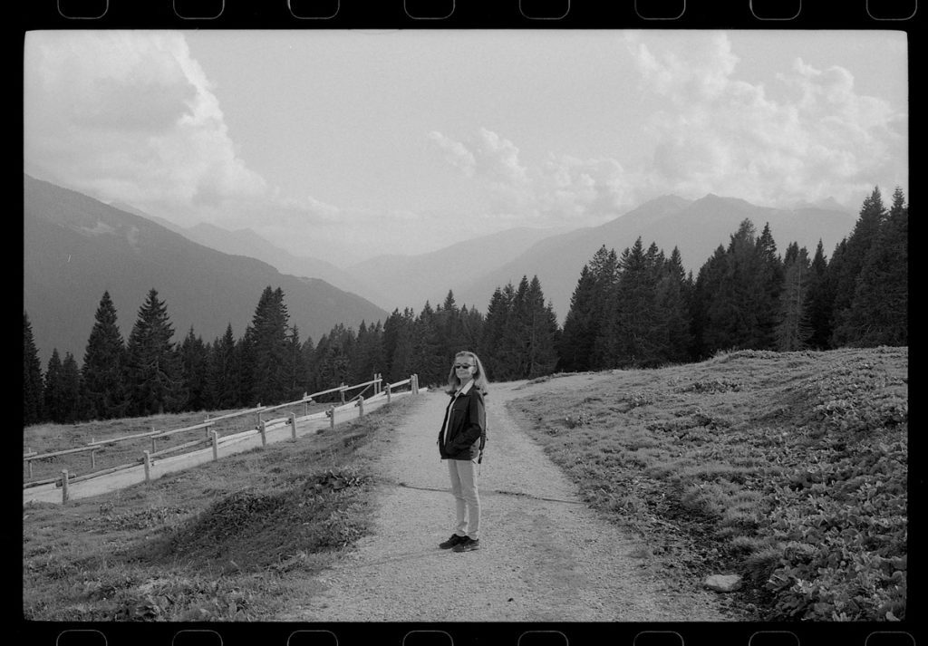 Black and white picture of a woman on a hike in the countryside with mountains