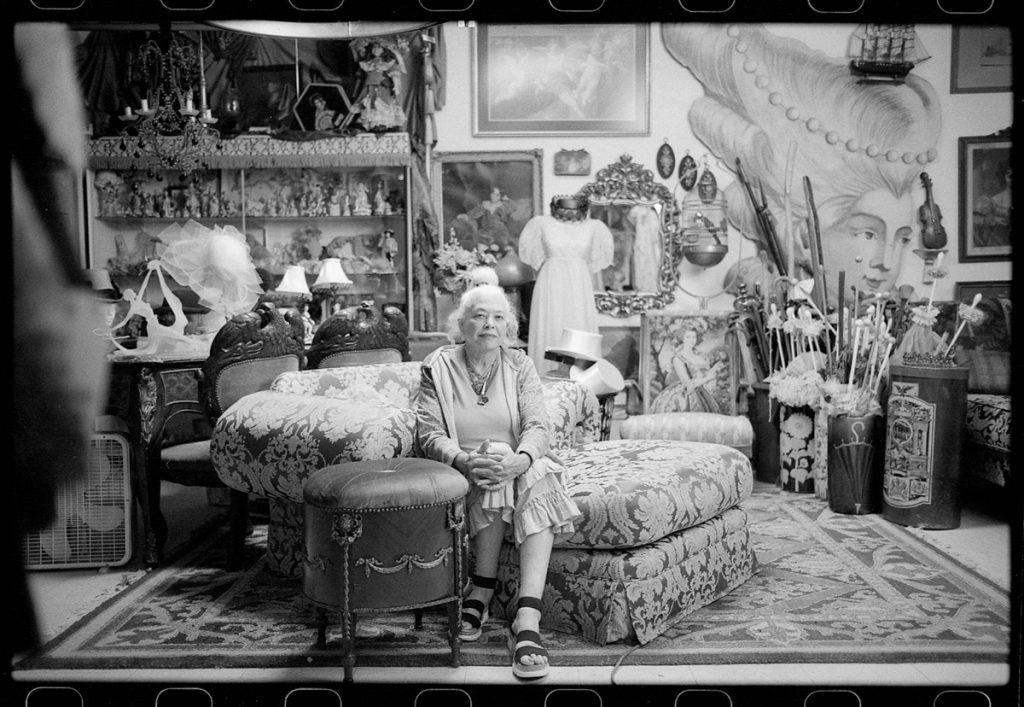 An old black and white woman sat in a dressing room