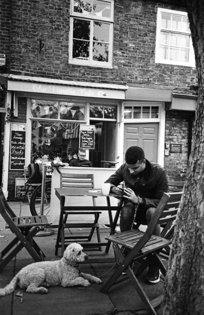 Man outside cafe shot by Peggy Marsh on a ricoh-ff7 with HP5 plus BLACK AND WHITE FILM